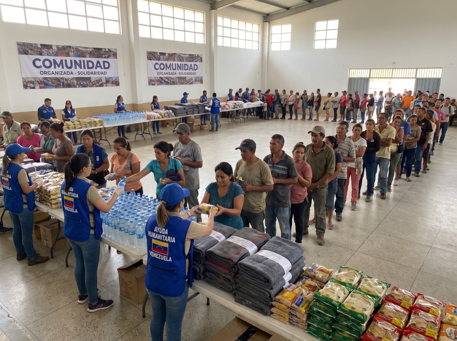 Voluntarios repartiendo agua, mantas y comida a familias en un punto de ayuda comunitario